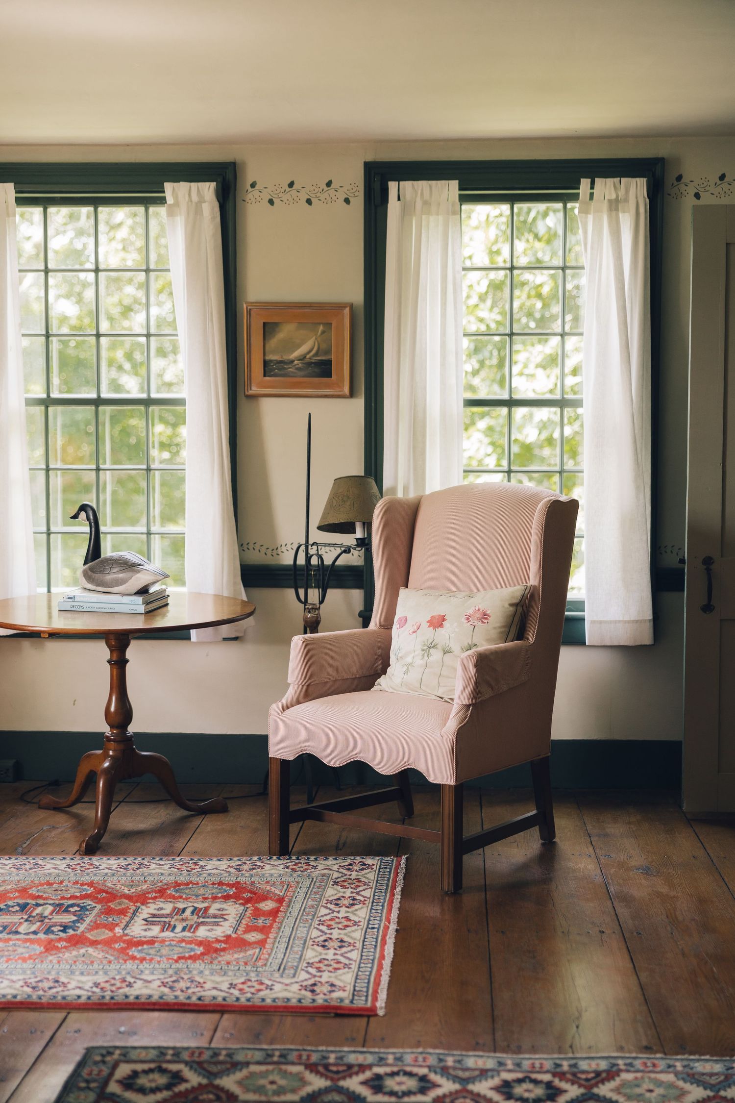 A series of four interior room views showing pink upholstered chairs, hardwood floors, and oriental rugs in a rustic setting.