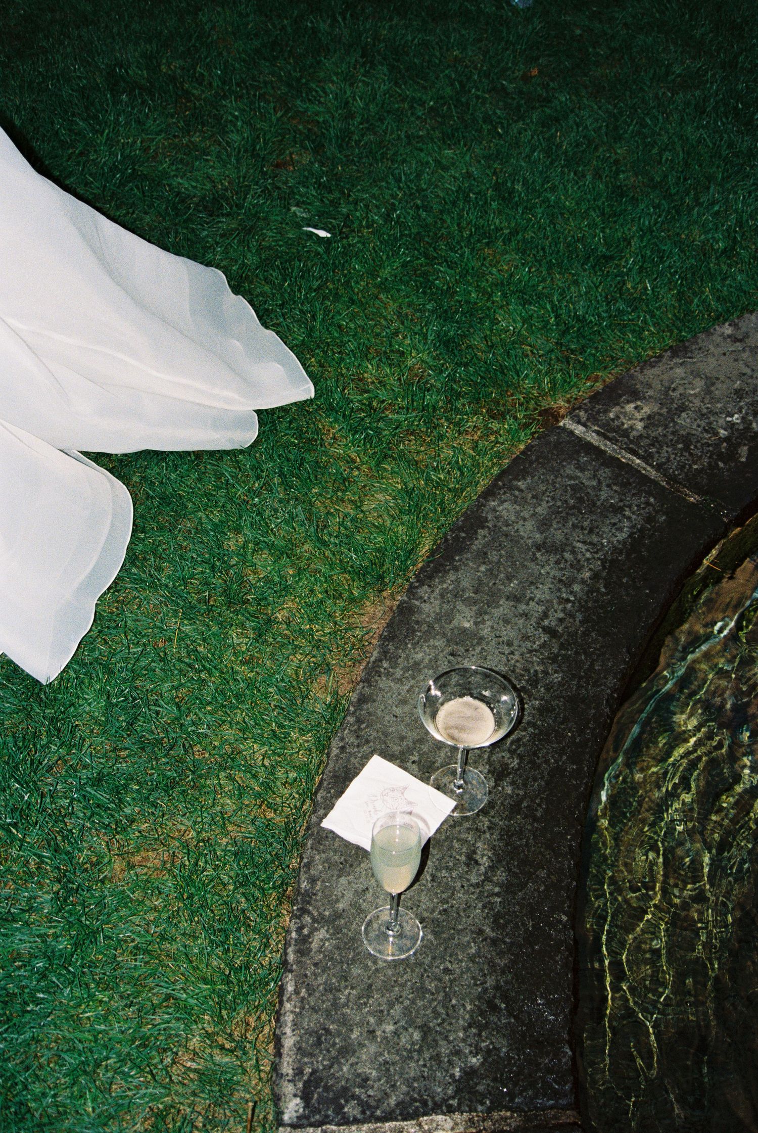 White fabric and glassware arranged on dark stone steps in a garden setting.