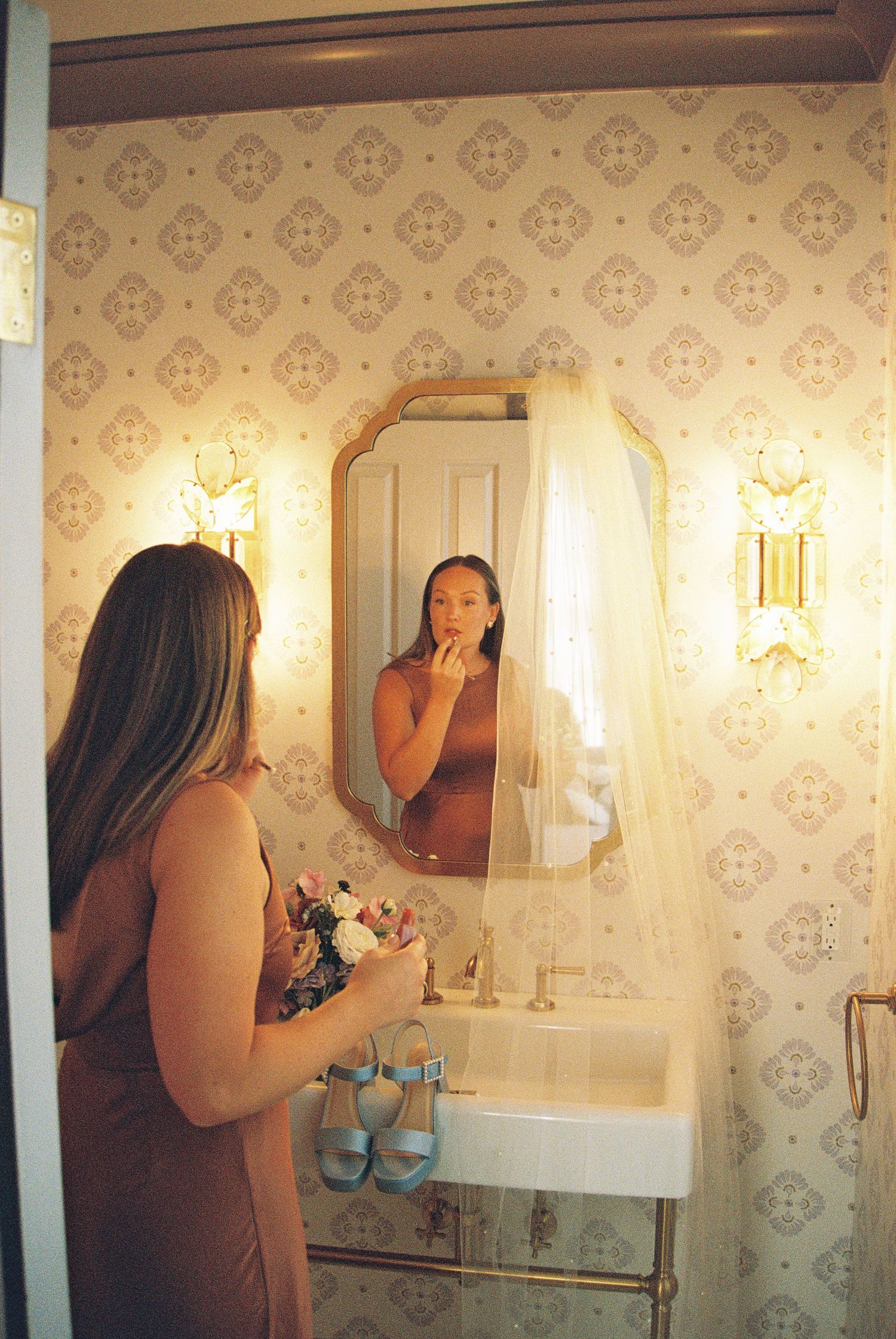 Interior shots of a bathroom with vintage wallpaper and wall sconces.