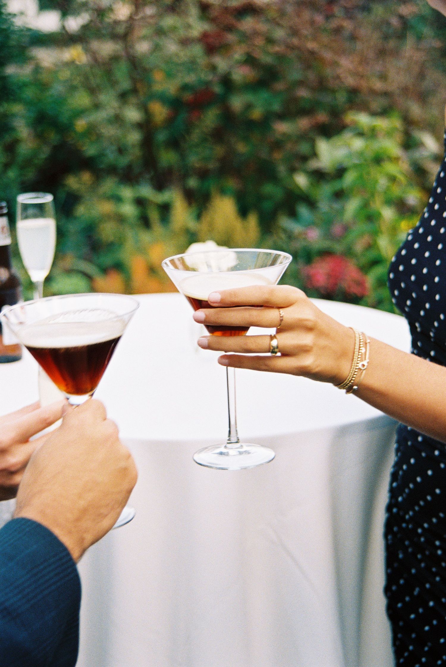 Close-up of hands holding wine glasses during an outdoor celebration.