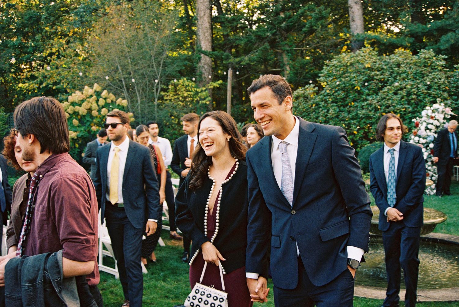 Wedding guests mingle on a lawn during an outdoor reception.