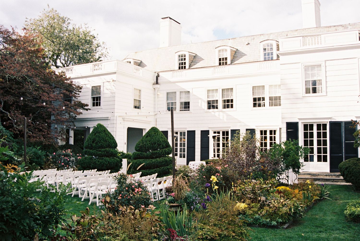 Elegant white mansion exterior with manicured gardens and classic architecture.