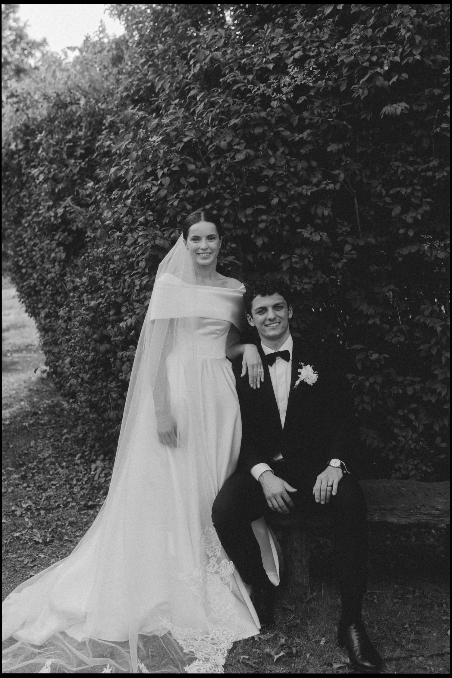 A black and white wedding photo series showing a couple posing outdoors against a garden backdrop.