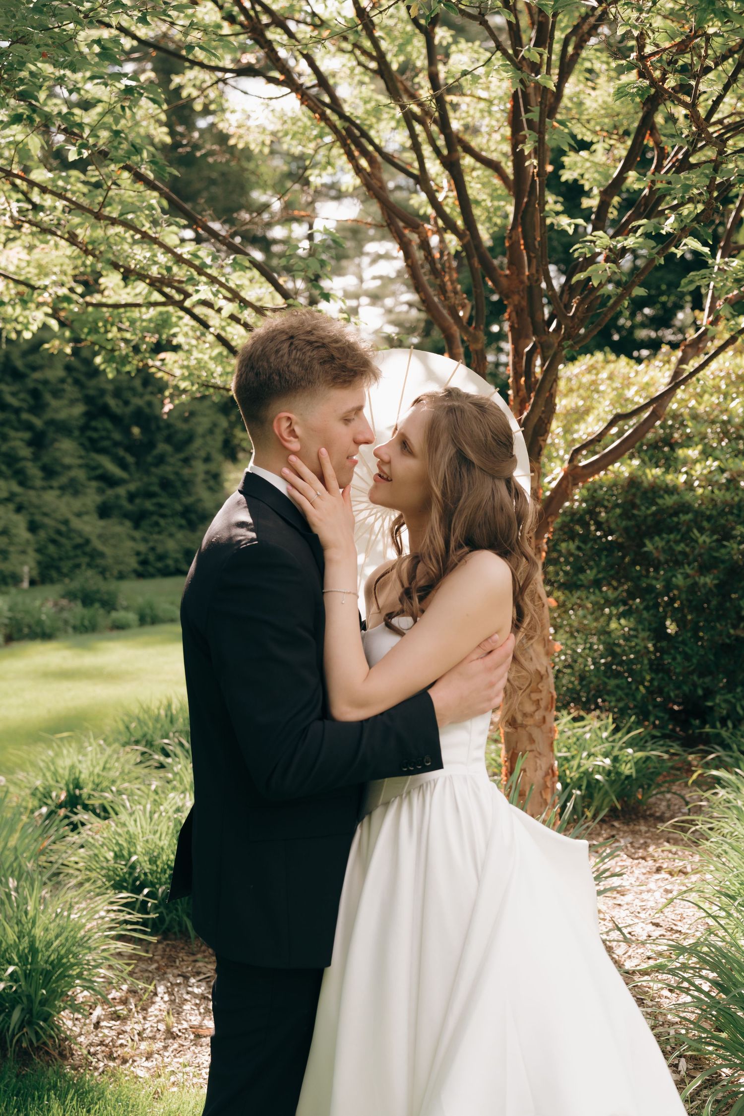 Romantic wedding couple shares intimate moments under blooming trees in a garden setting.