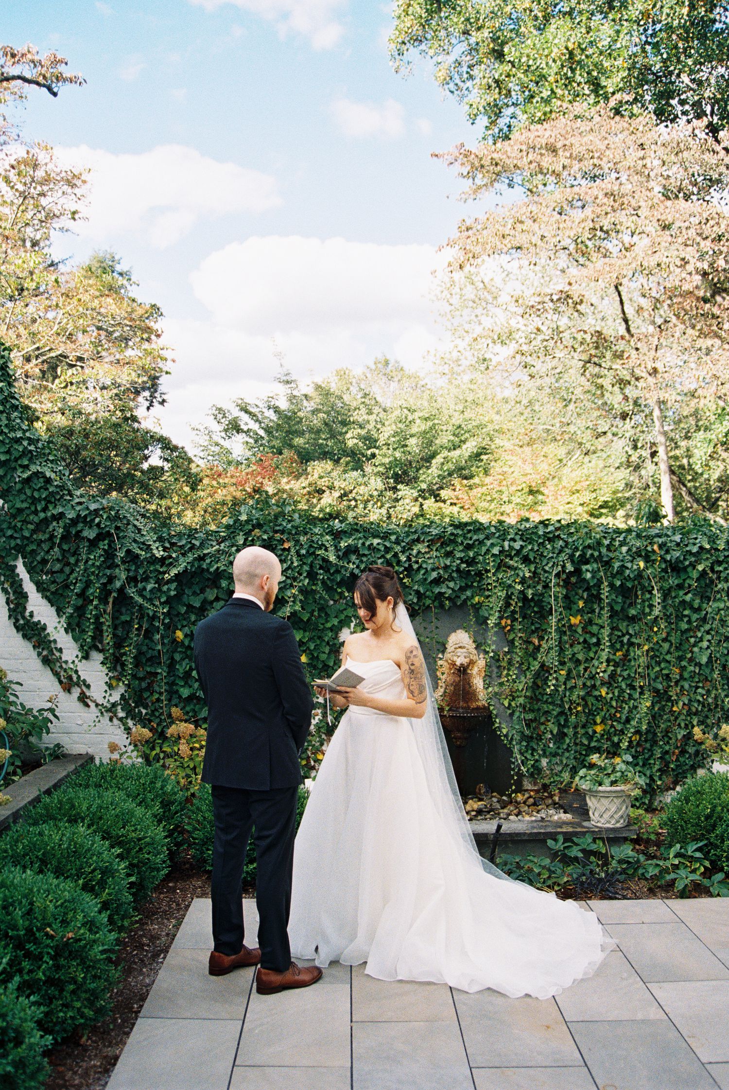 Wedding ceremony setup on stone patio surrounded by lush garden landscaping.