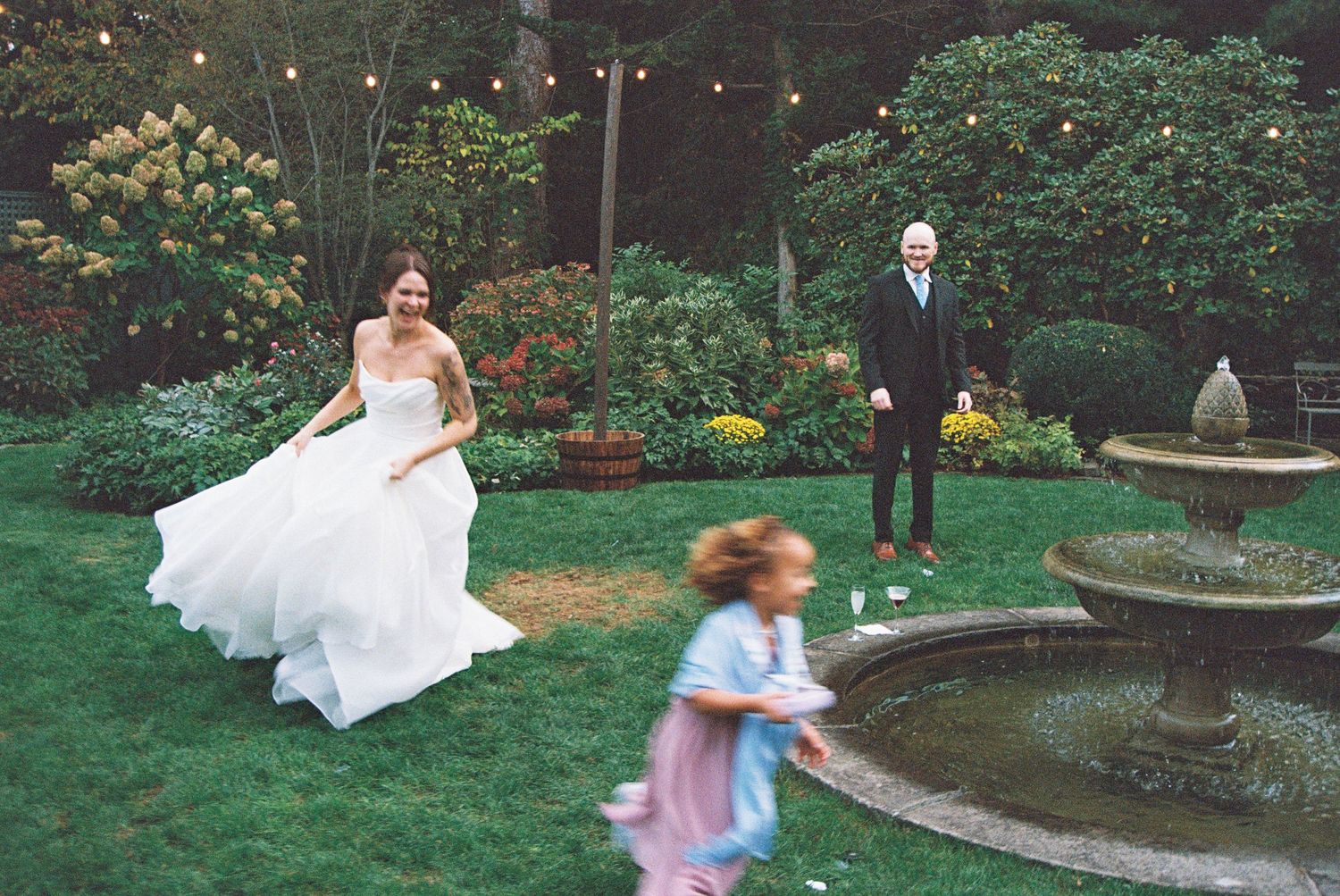 Garden wedding scene with string lights and decorative water fountain.
