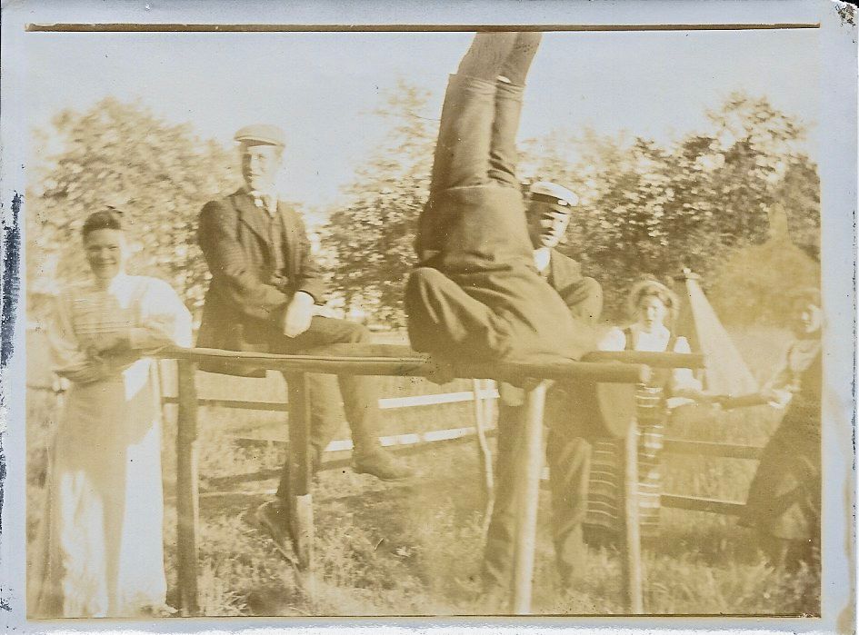 1920-luvun ihmisiä hassuttelemessa nojapuilla kesäisessä maisemassa.