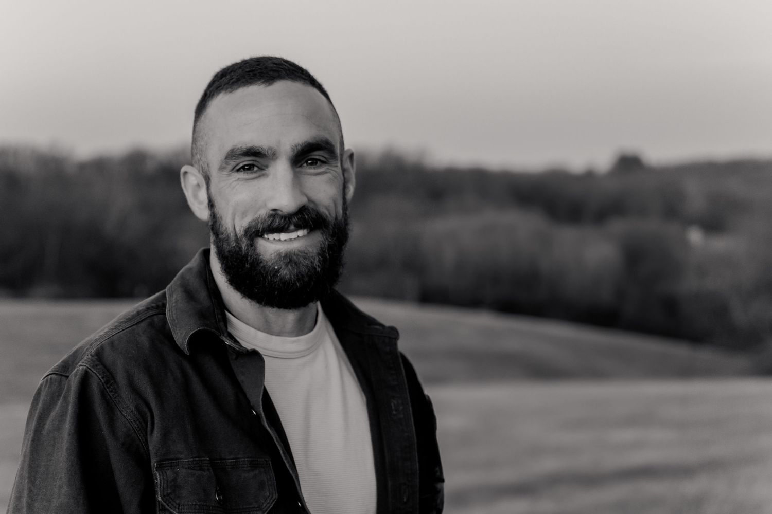 A series of black and white headshots showing different facial expressions and poses against outdoor backgrounds.