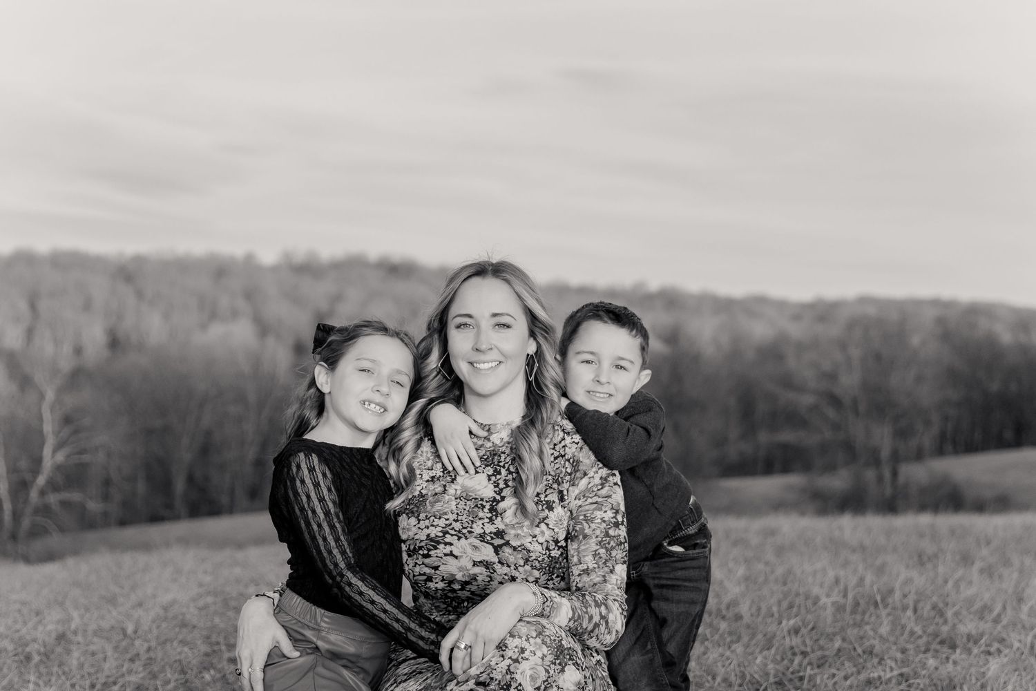 Family lying together in a grassy field on a sunny day.