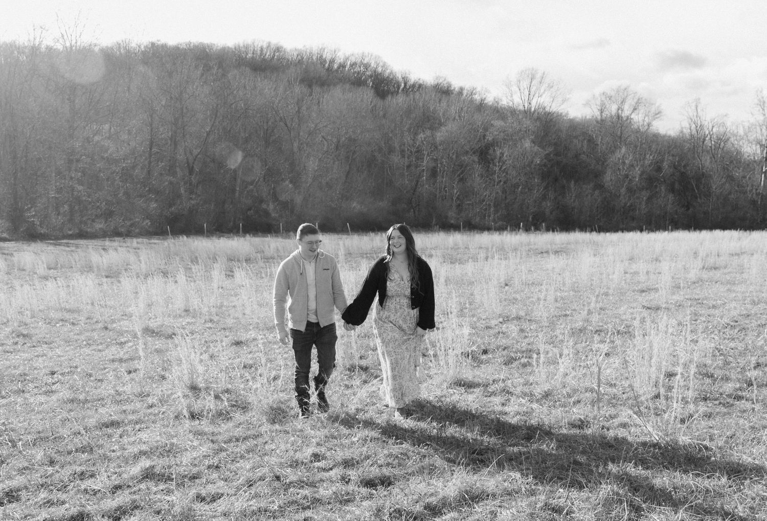 Two people walking hand in hand across an open field in black and white photography. Maryland photographer Shawn Michelle.