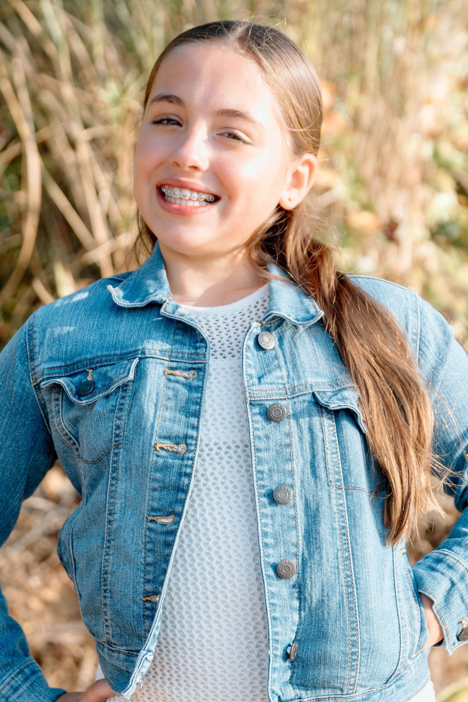 Side views of someone in a blue denim jacket and polka dot shirt with a ponytail hairstyle.