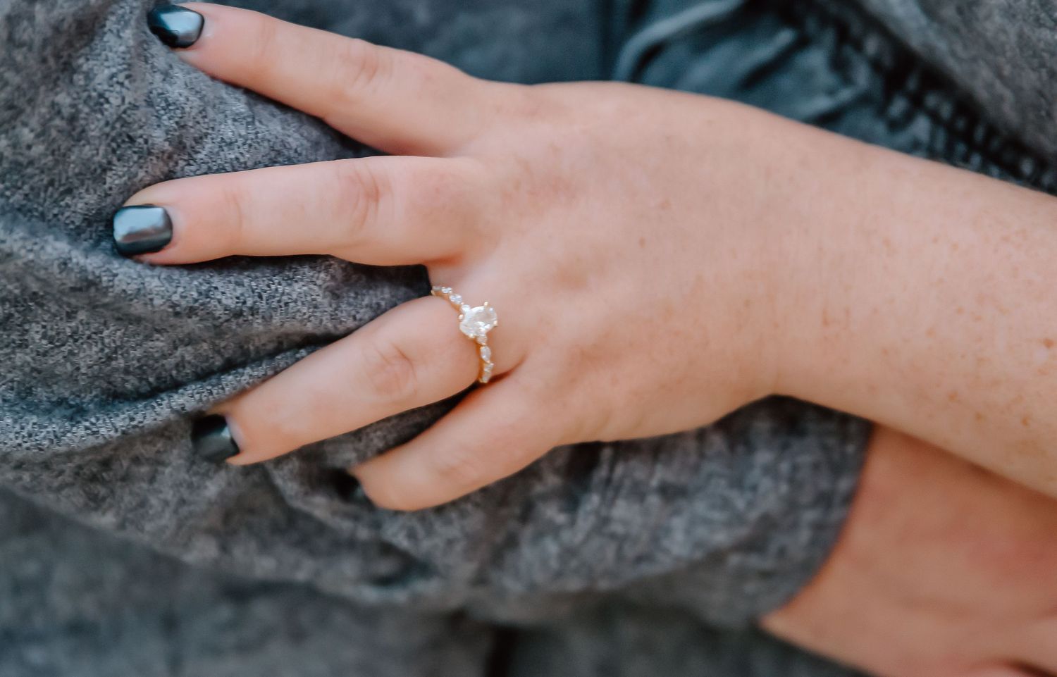 Close-up of a elegant diamond solitaire engagement ring on a gold band worn on a woman's hand.