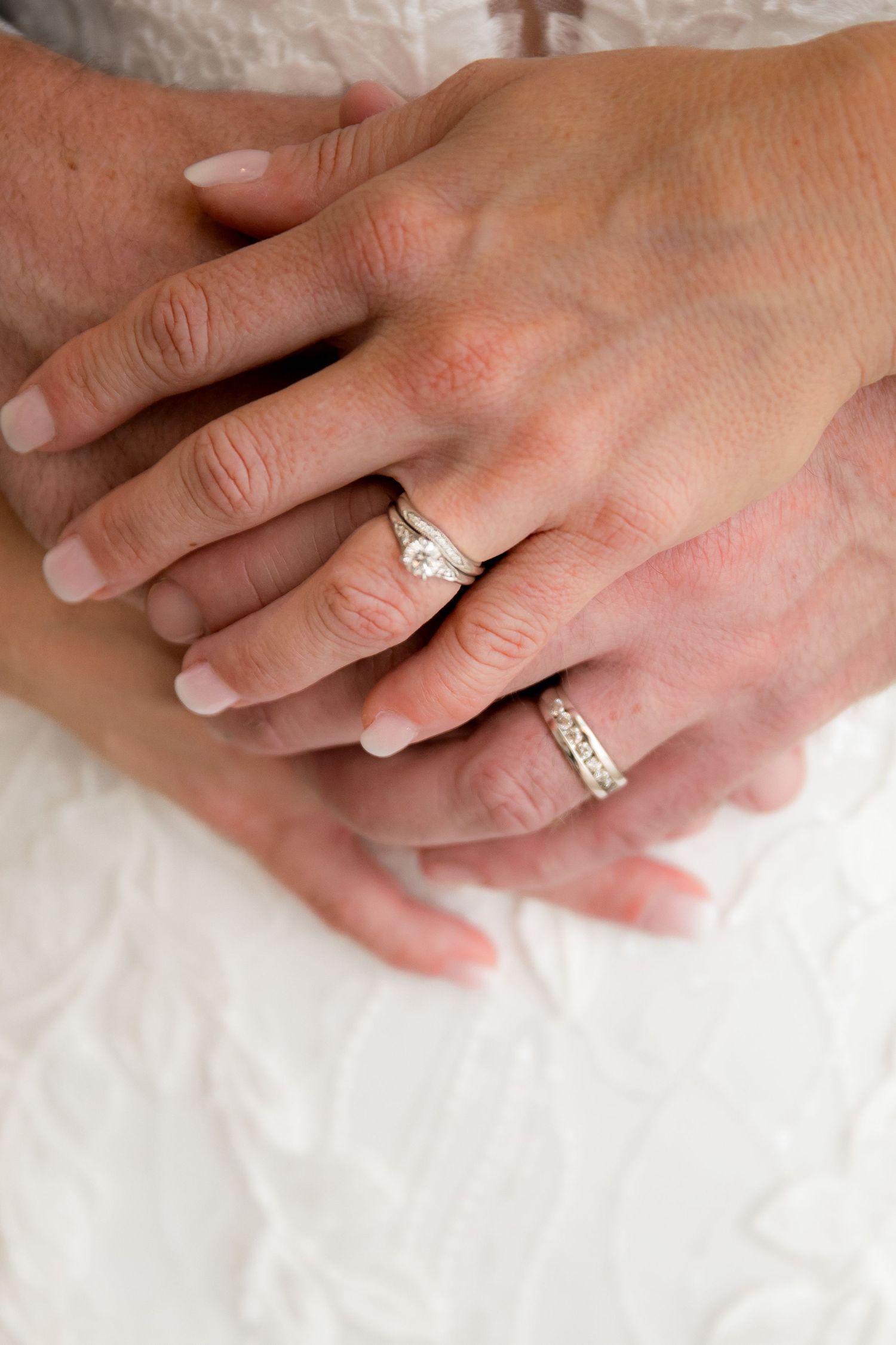 Close-up sequence showing hands wearing a sparkling engagement ring against a white fabric background.