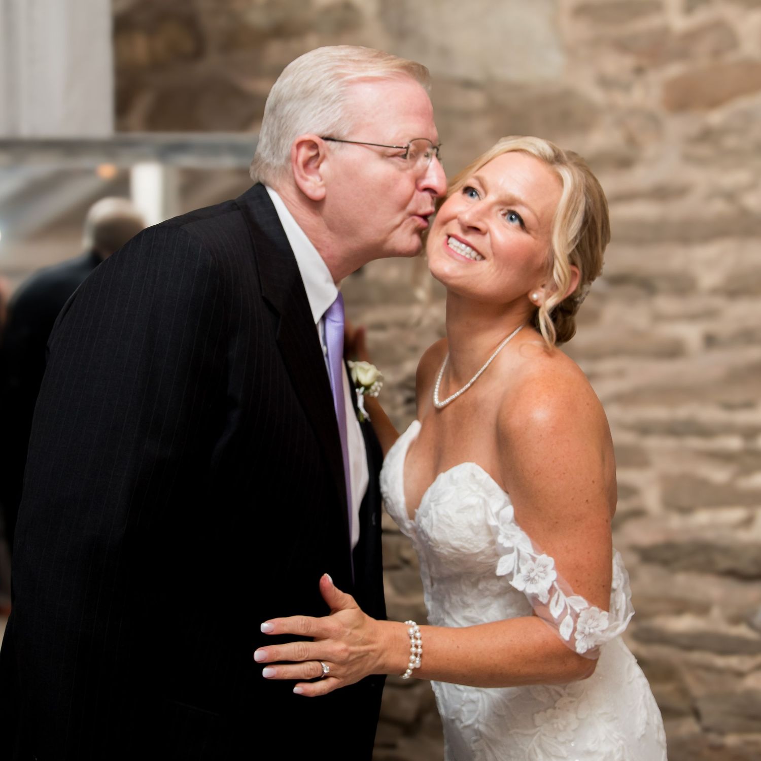 Close-up shots of emotional moment during wedding ceremony with stone wall background.