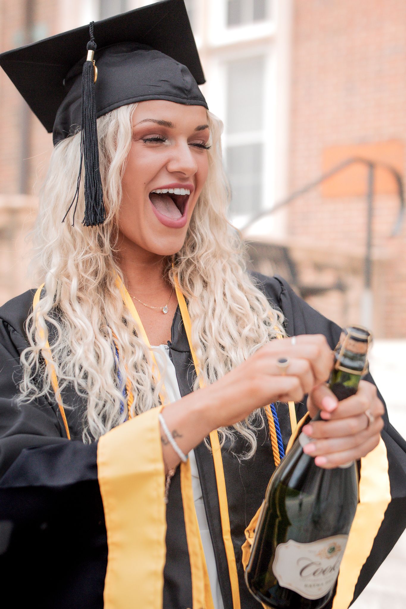 A sequence showing a graduate in cap and gown opening a champagne bottle during a celebratory moment.