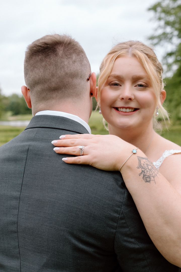 Close-up sequence of a wedding couple embracing showing details of the dress, veil, and jewelry against a natural backdrop.