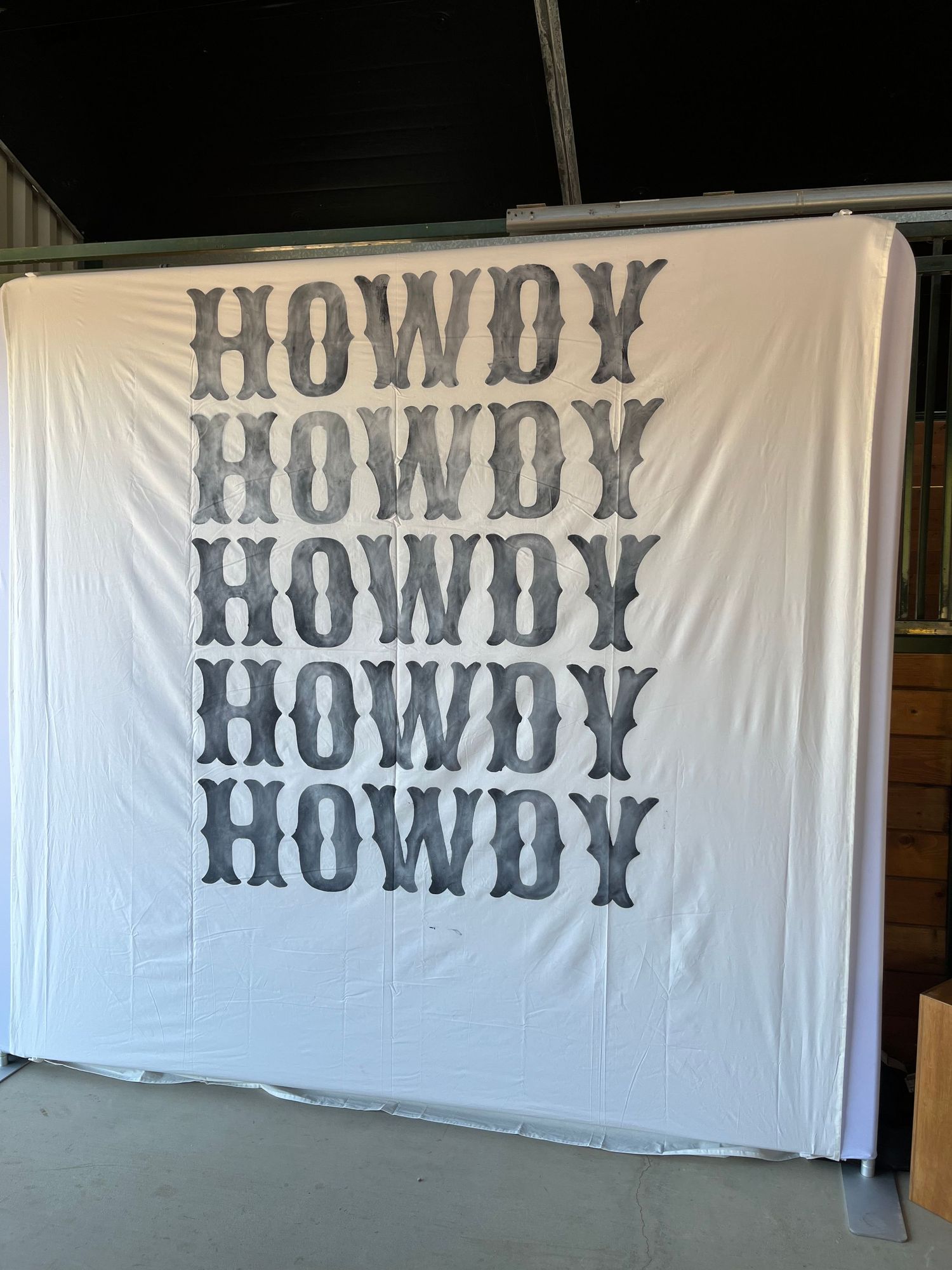 A white backdrop with the word 'HOWDY' repeated five times in gray western-style typography arranged vertically.