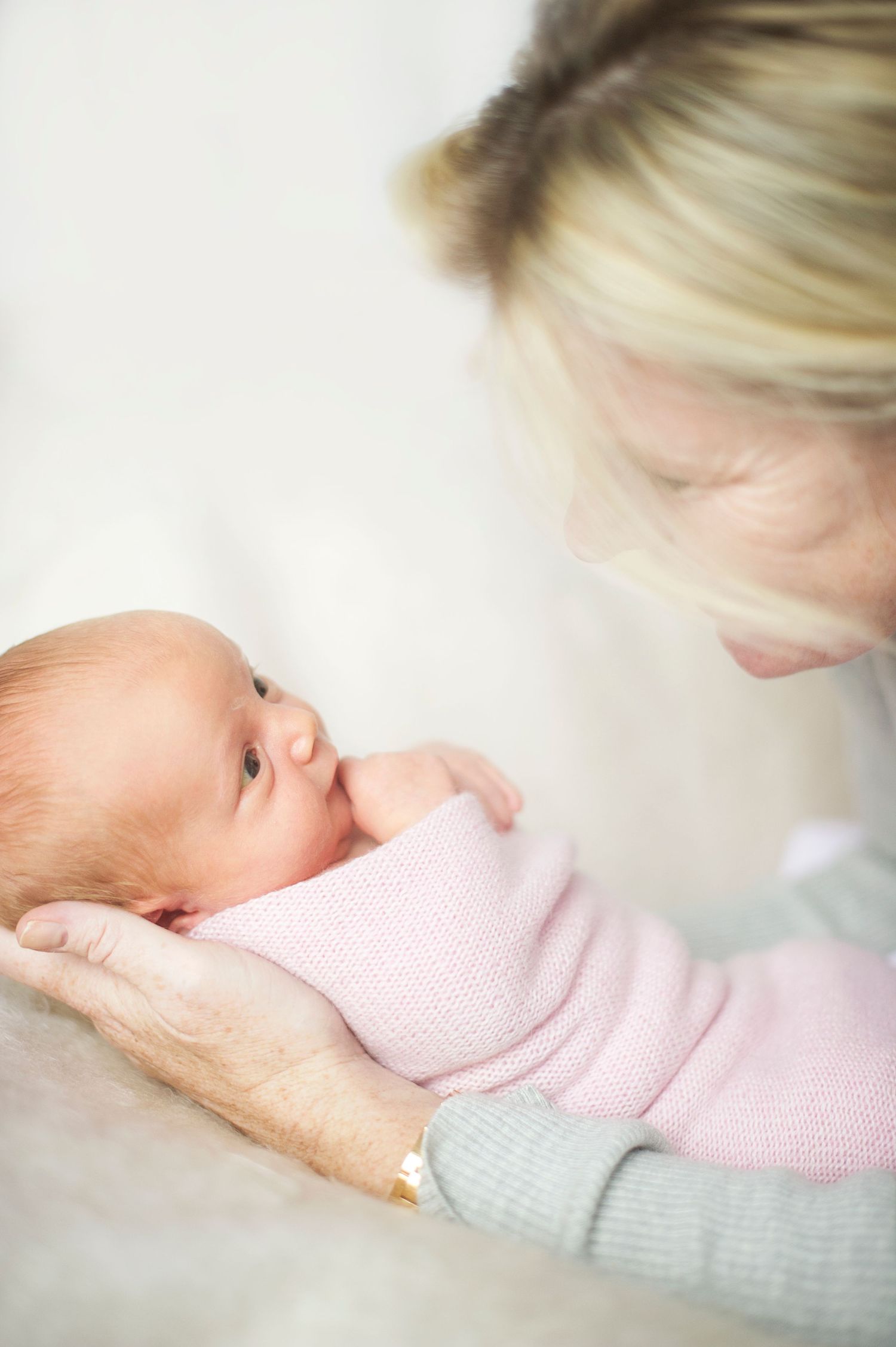 Mother looking lovingly at newborn baby in swaddle. Captured by newborn photographer Phoebe Lee Photo in Toronto, Ontario.