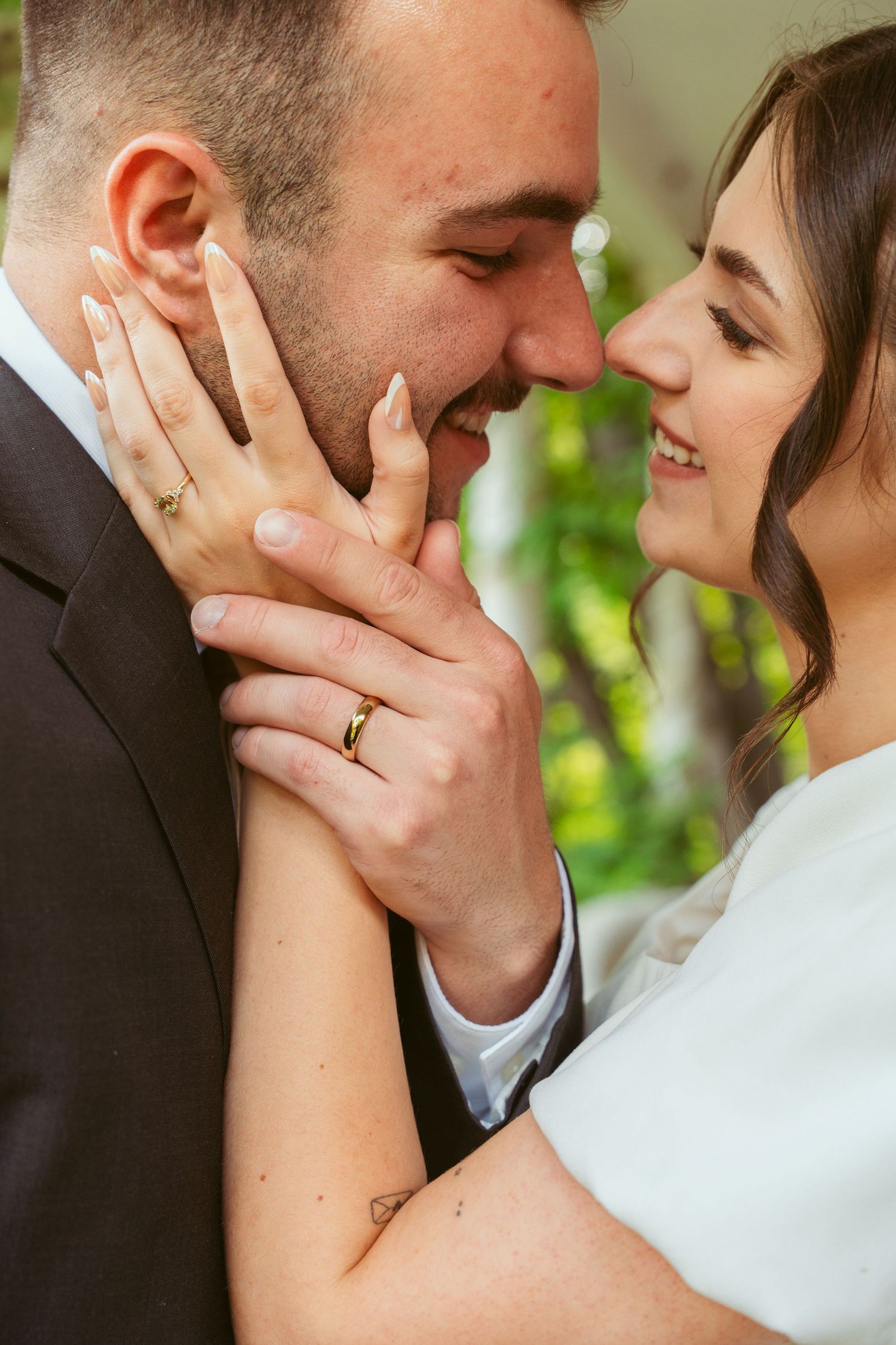 Close up side view of tender romantic wedding couple moment outdoors in lush garden setting.