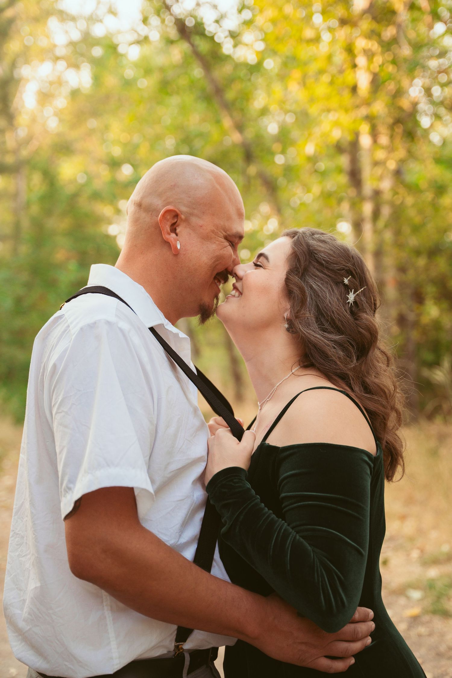 A romantic couple shares a tender kiss in a beautiful outdoor setting with golden autumn lighting and foliage.