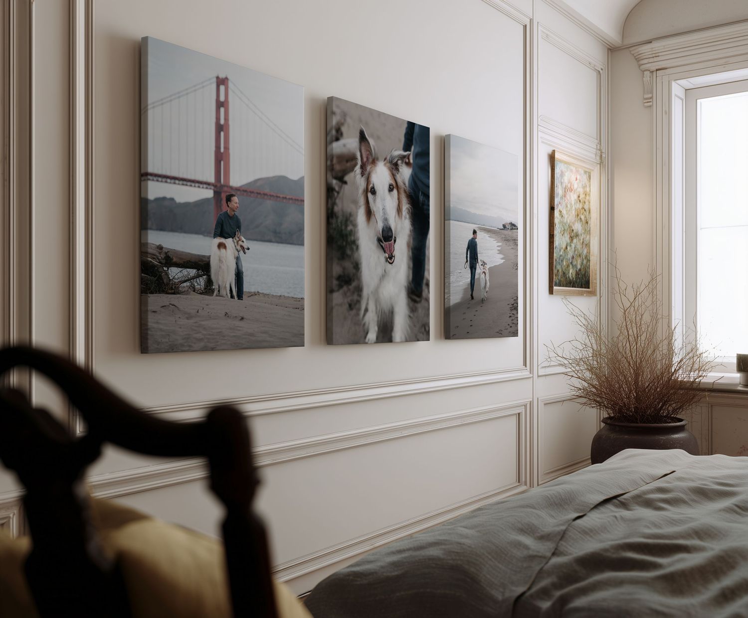Three canvas prints of a dog at the Golden Gate Bridge displayed above a bed in a cozy bedroom.