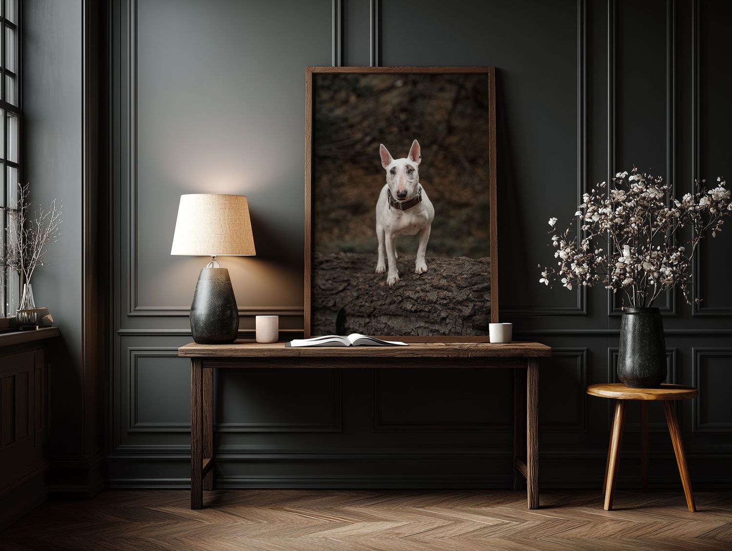 Framed portrait of a white Bull Terrier dog displayed on a wooden console table in a dark elegant room.