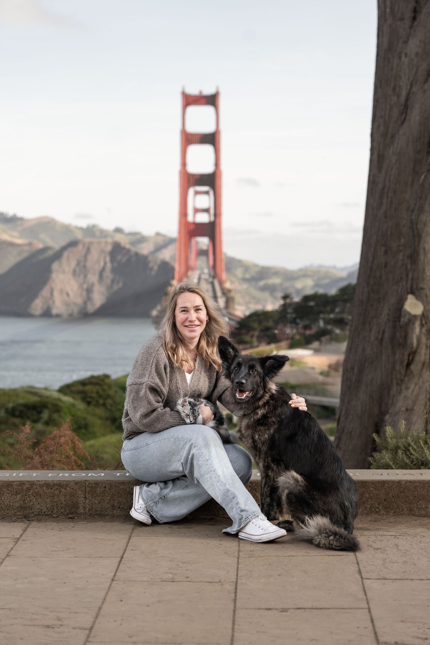 Woman smiling with her German Shepherd dog at the Golden Gate Bridge overlook in San Francisco.