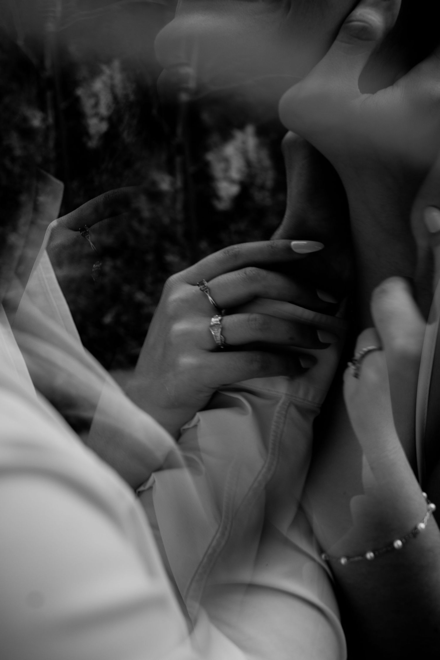 B&W engagement shot—he holds her neck, she grips his arms, gazing up with love and intensity. Raw, timeless connection.