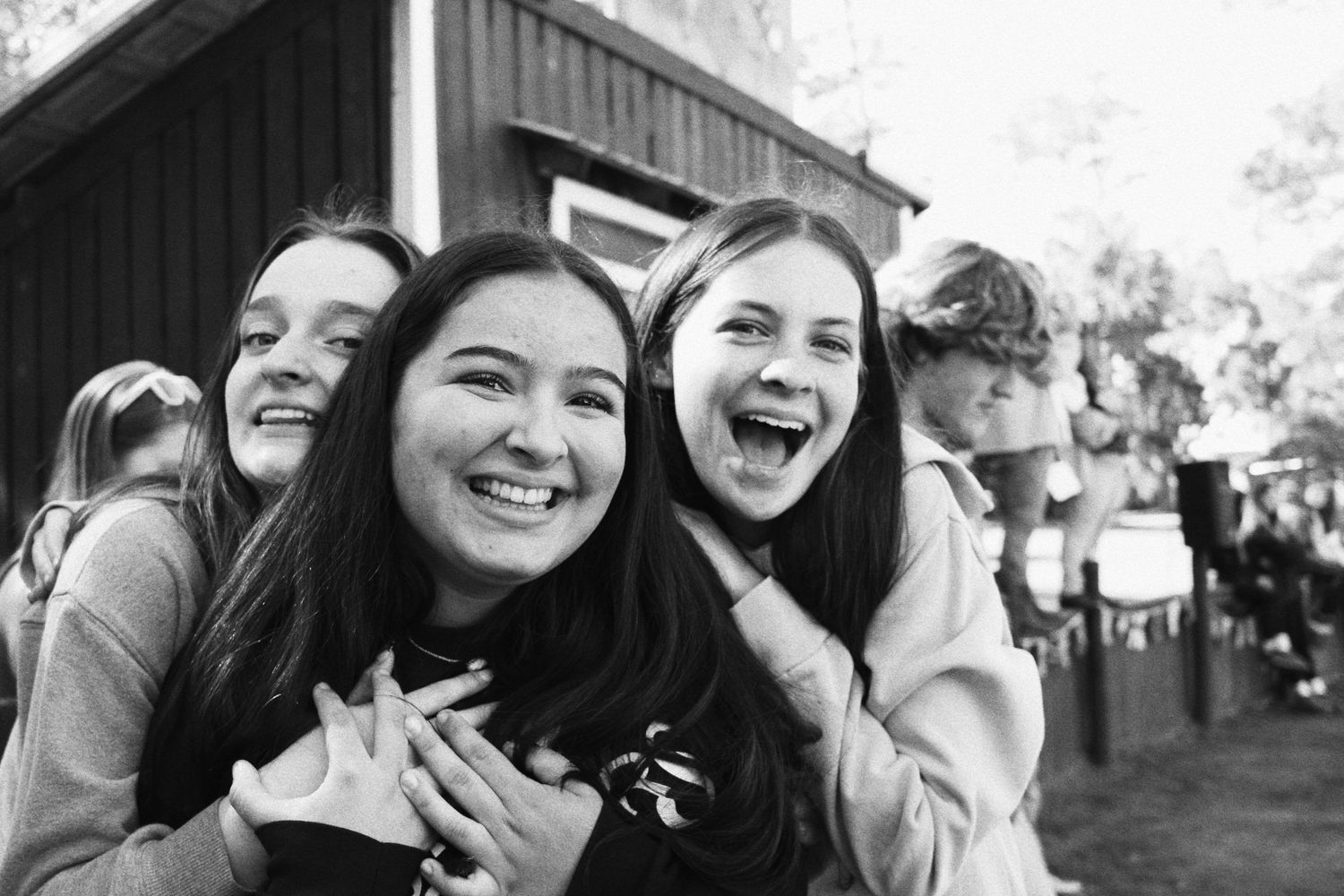Black-and-white photo of three high school girls hugging each other