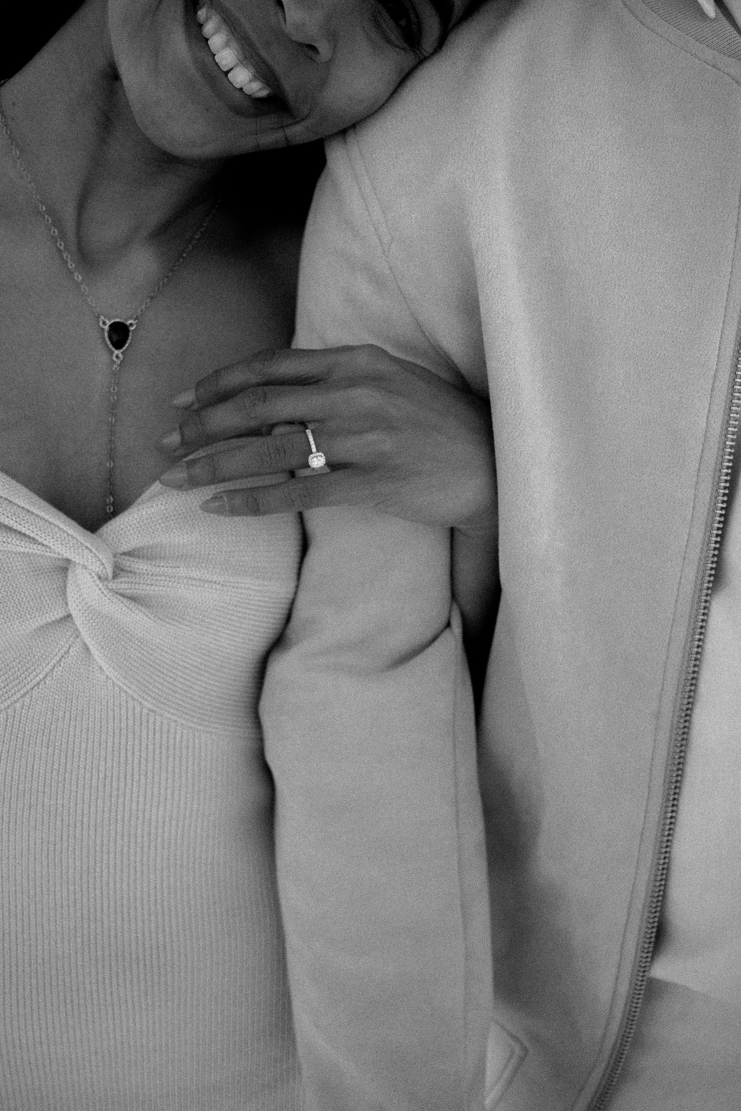Engaged couple photo with the girl leaning her head on her fiancé's arm, holding his arm and showing off her engagement ring.