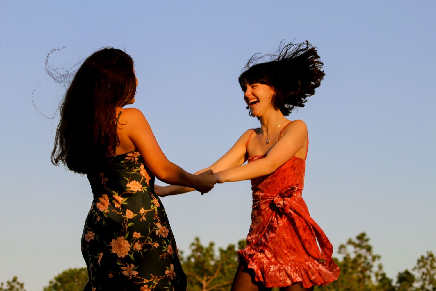 Friends jumping and holding hands with the blue sky as the background, creating vibrant Gucci vibes.
