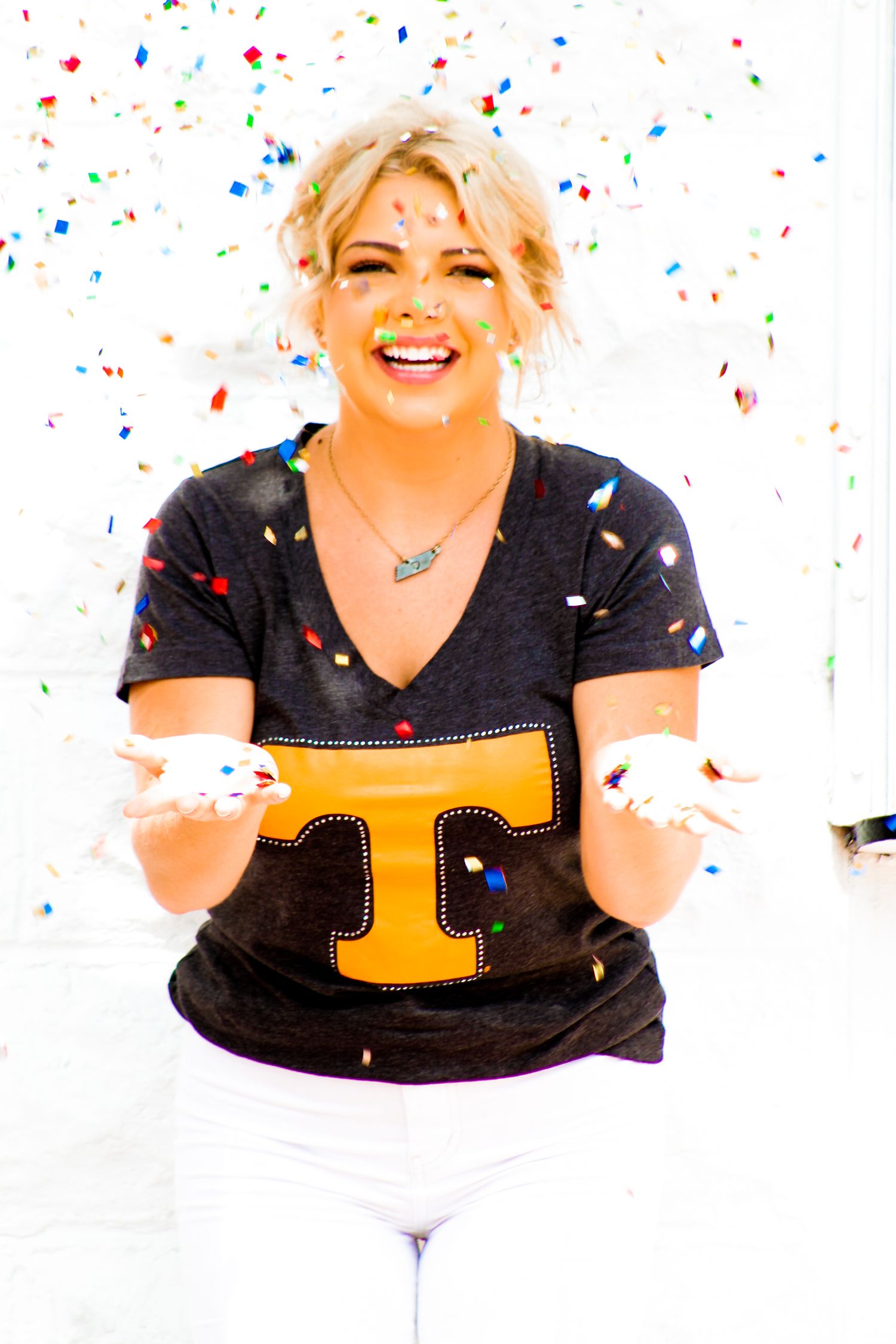 Graduation photo of a girl holding her hands out as confetti falls, creating a celebratory atmosphere as she embraces the excitement of the