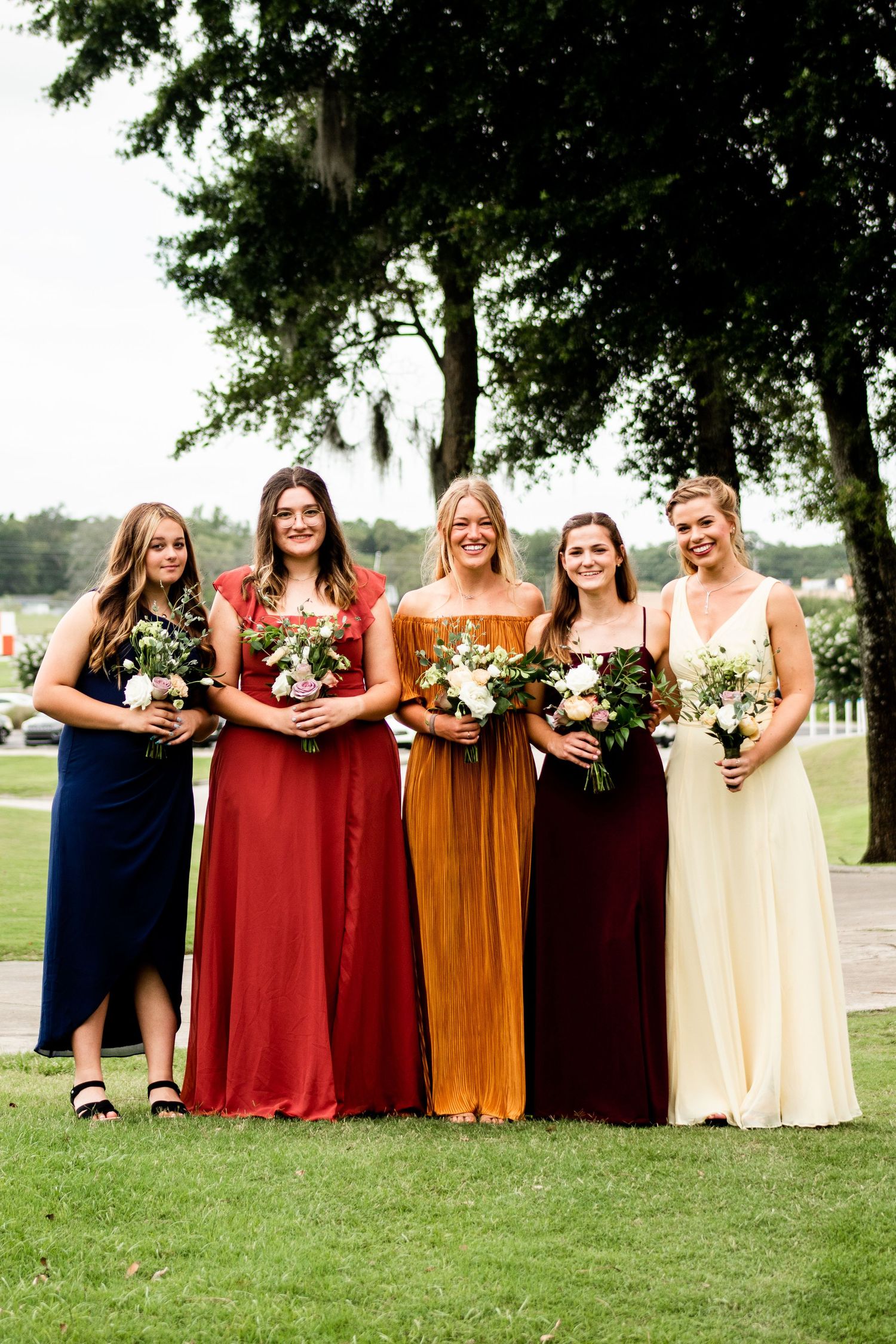 Photo of bridesmaids smiling, each wearing different colored autumn dresses.
