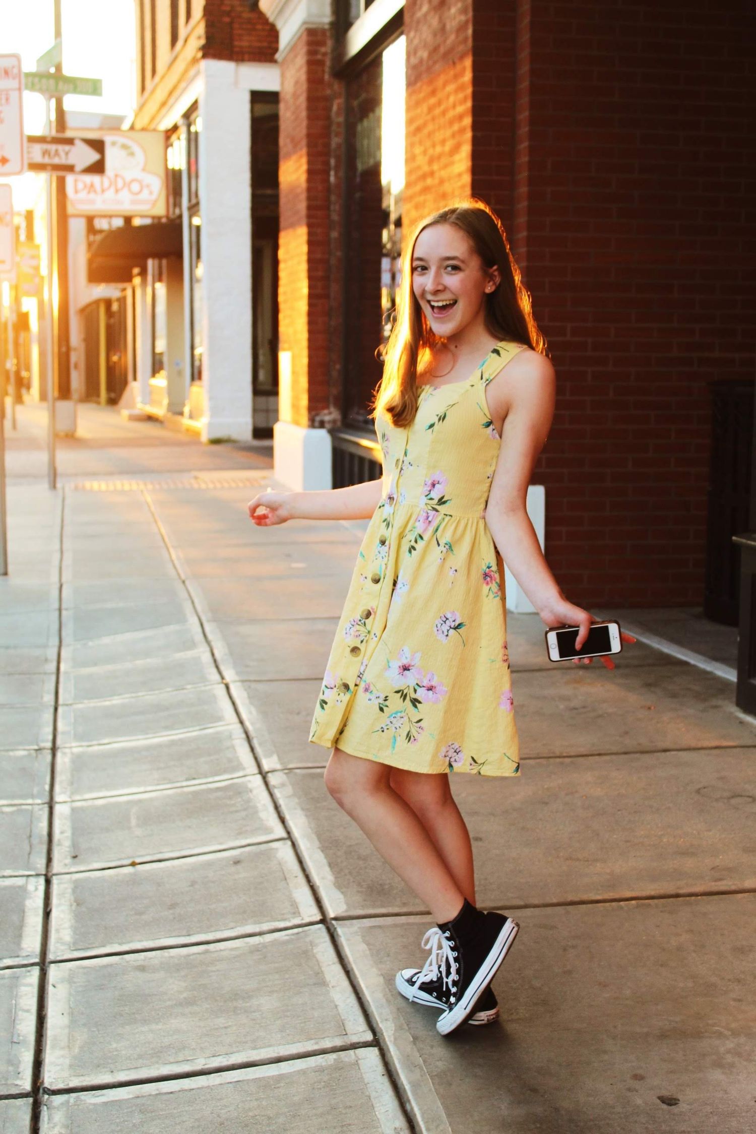 Graduation photo of a girl standing downtown, with the sunset hitting her from behind