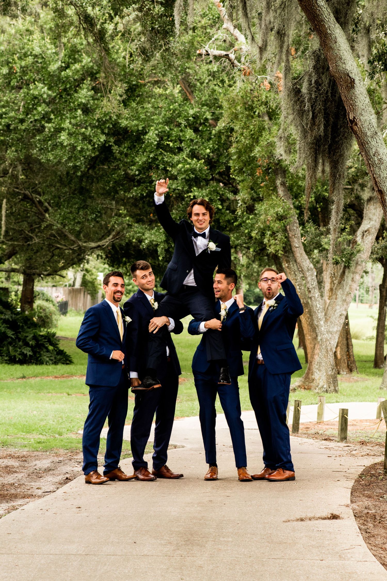 Groomsmen holding up the groom in celebration, cheering joyfully together.