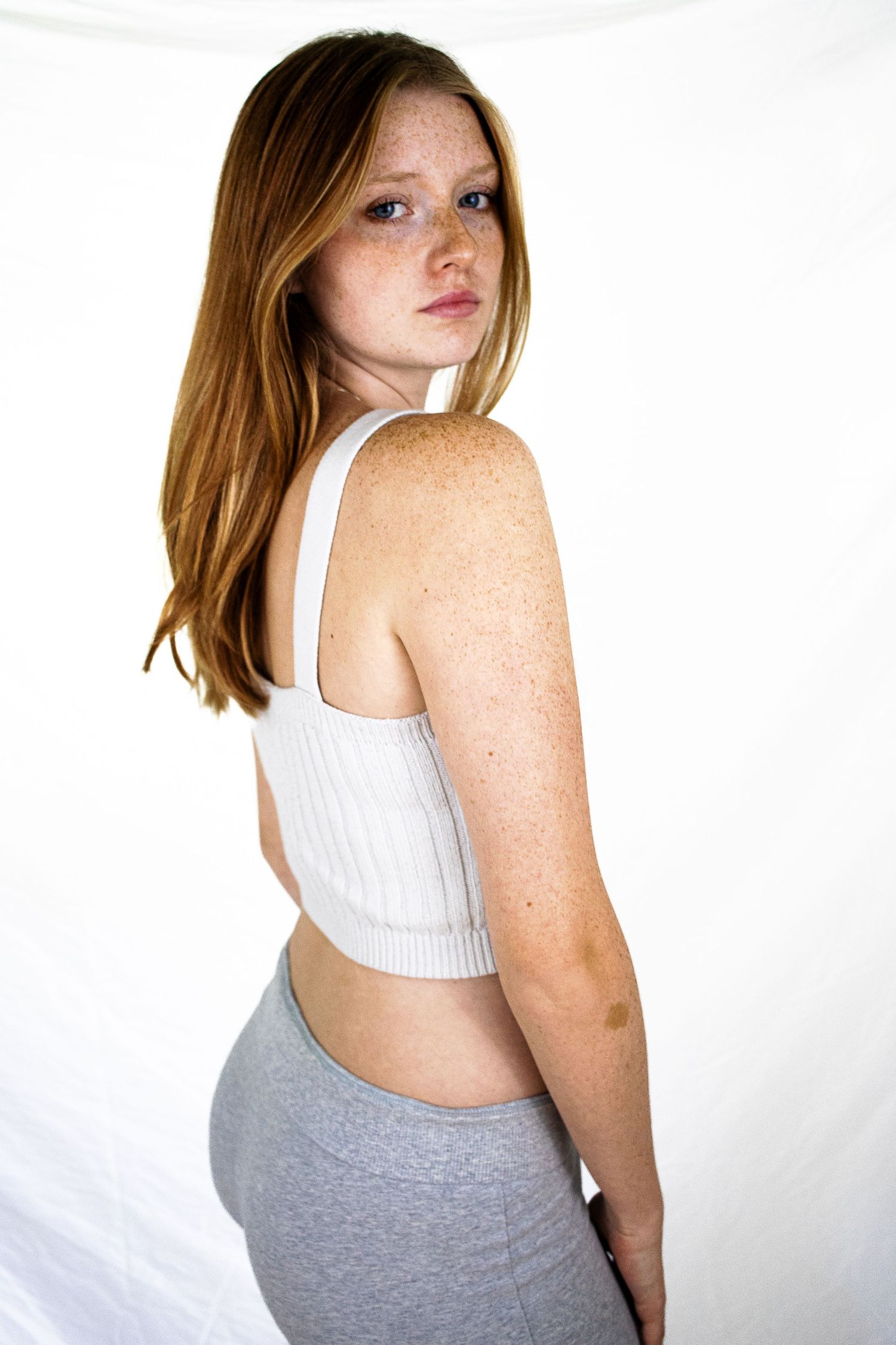 Full-body shot of a red-haired, freckled model posing against a white background for an agency portfolio.