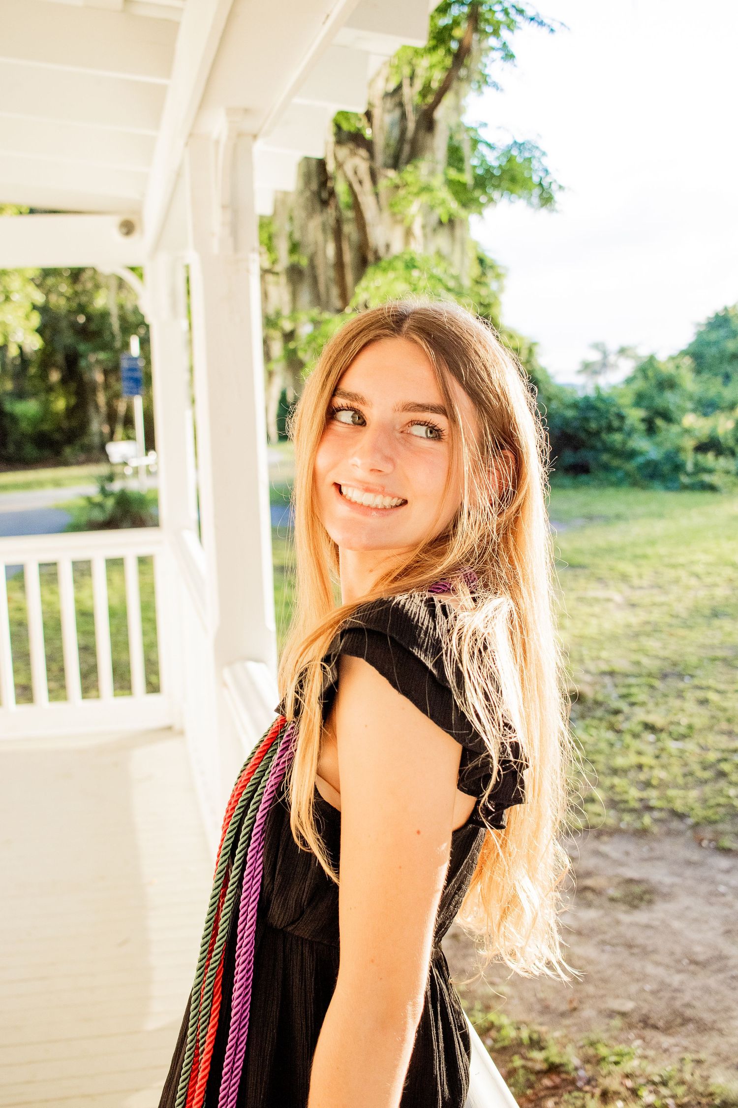 Graduation photo of a girl waist-up, with sunlight hitting her as she gazes past the camera.