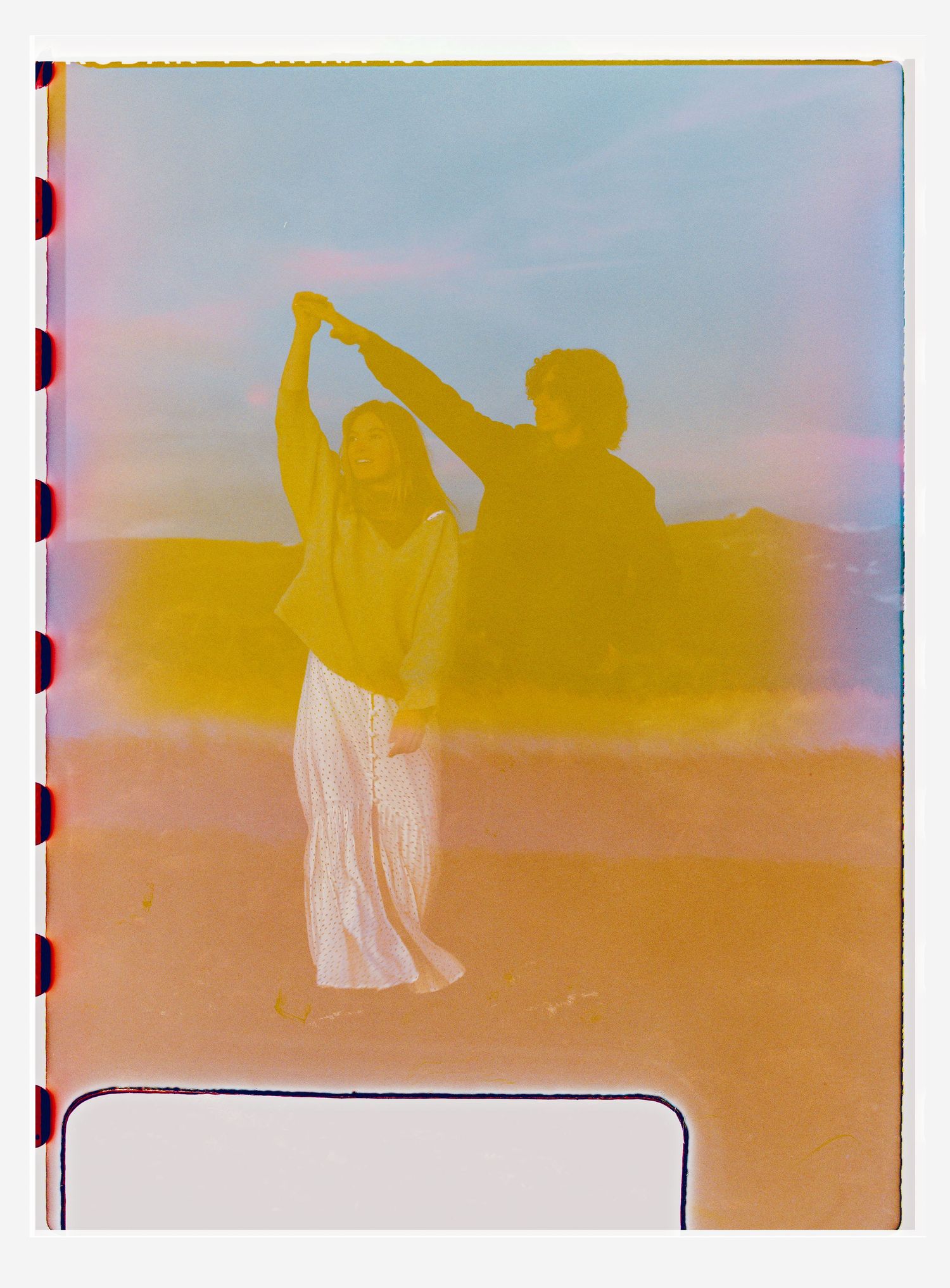 Two figures dancing together in warm yellow hues, painted in a dreamy film strip style with soft pastel tones.