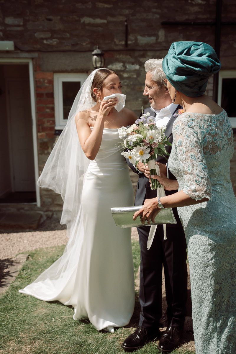 Wedding party members in mint green and white dresses share candid moments during outdoor photo session.