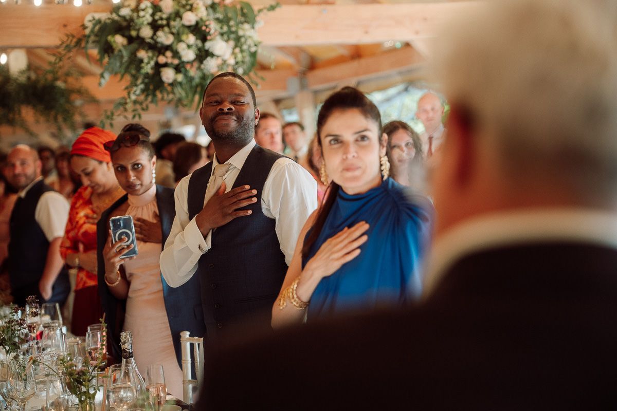 Guests enjoying an emotional moment during a wedding reception with floral centerpieces and candlelit tables.