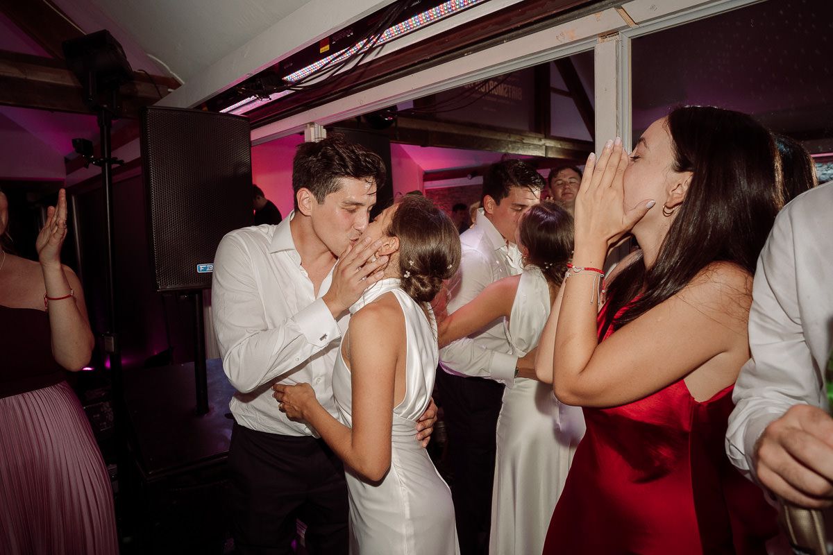Couples dance together at a wedding reception party with pink and purple lighting creating a festive atmosphere.