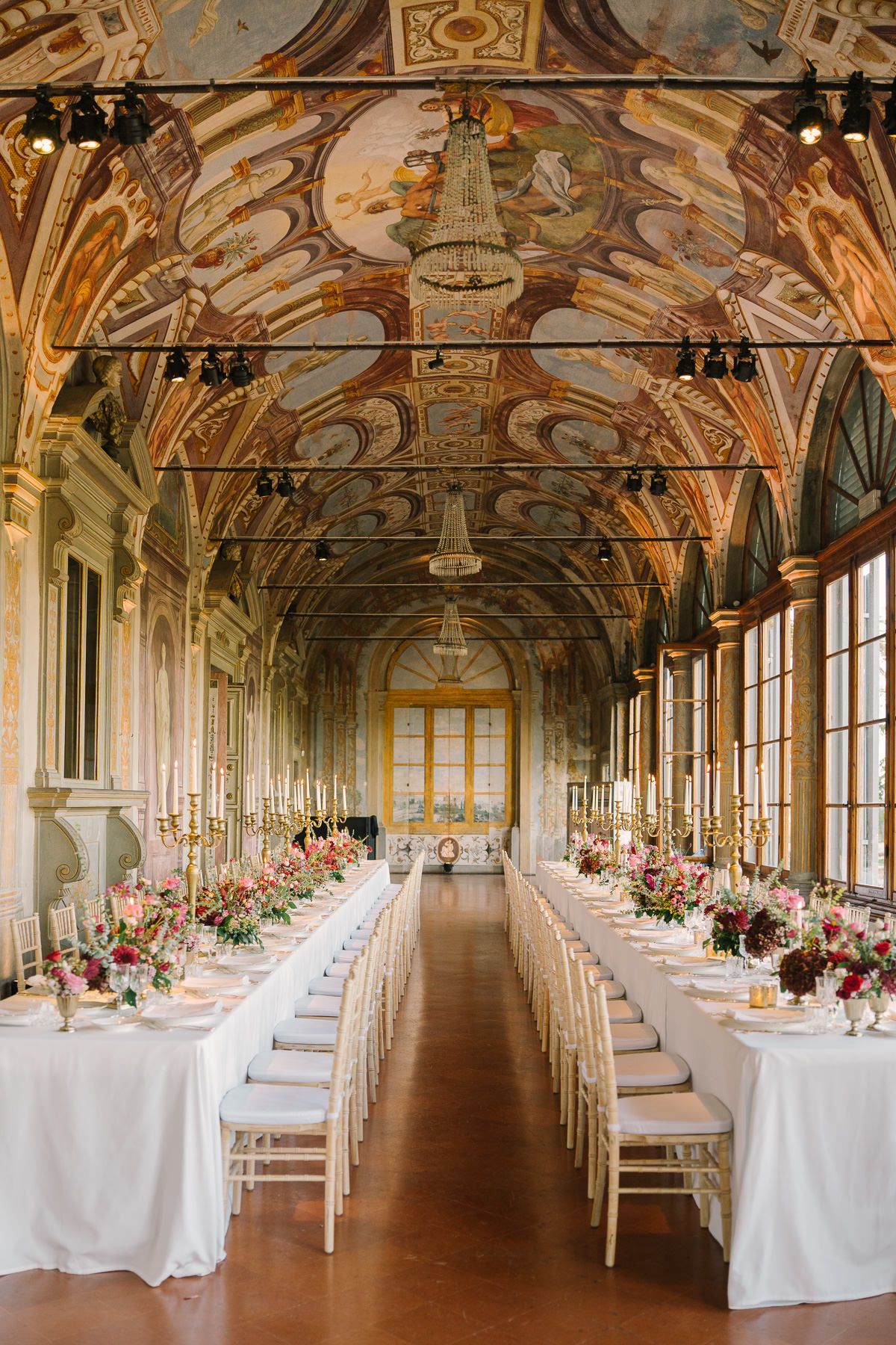 This image depicts a grand, ornate hall with intricate ceiling decorations and a long table set for a formal event.