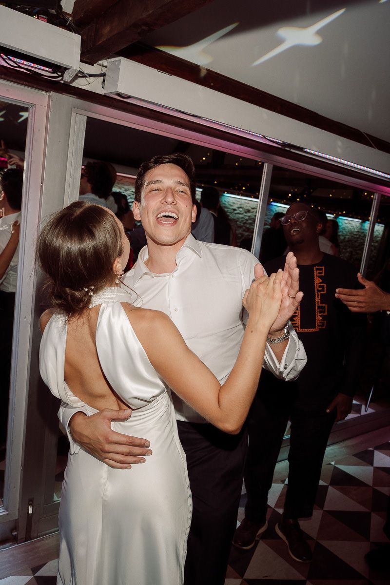 A couple dances together at an indoor event, sharing an intimate slow dance moment on the dance floor.
