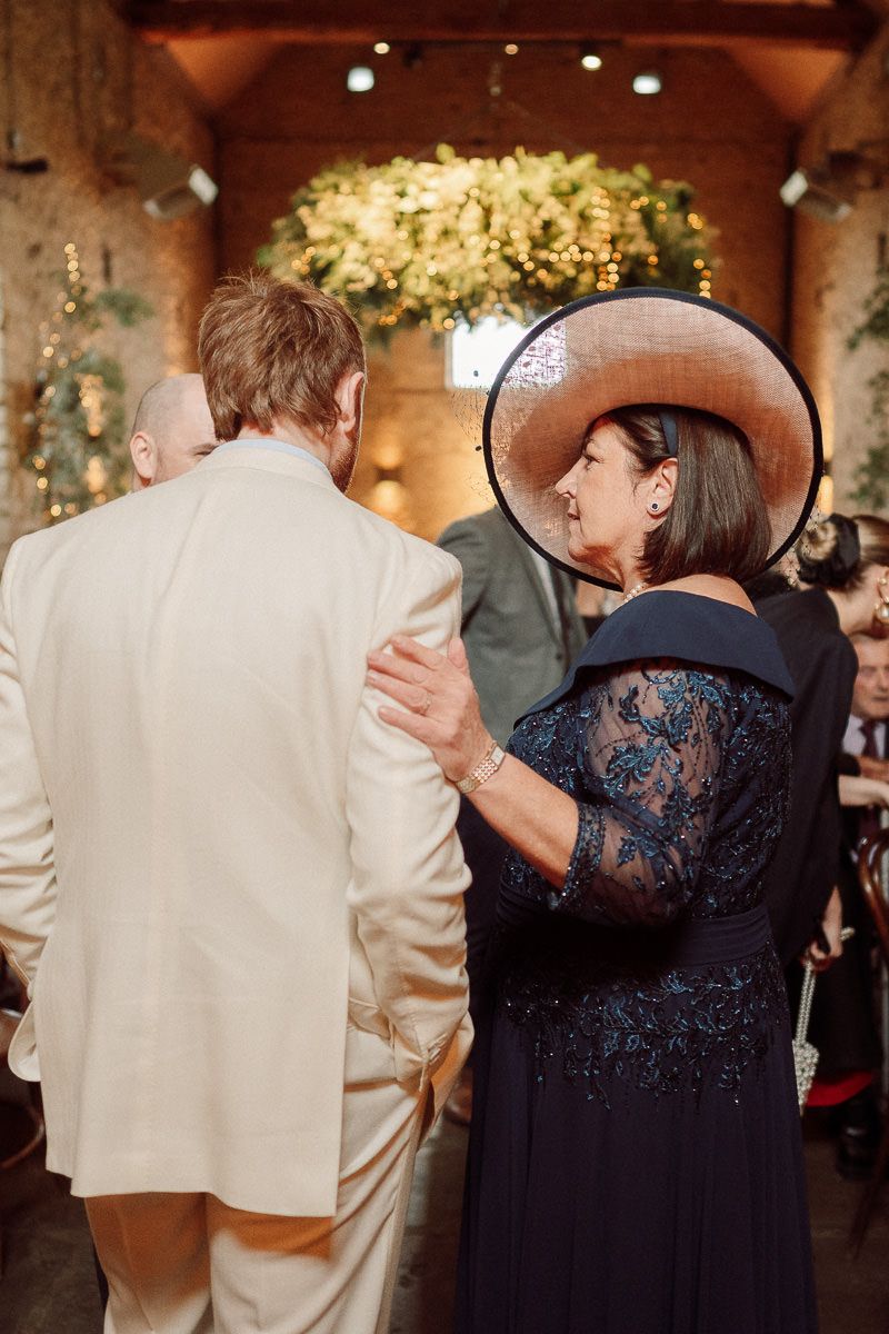 Wedding guests in formal attire dance together during a reception celebration with warm lighting and decorative elements.