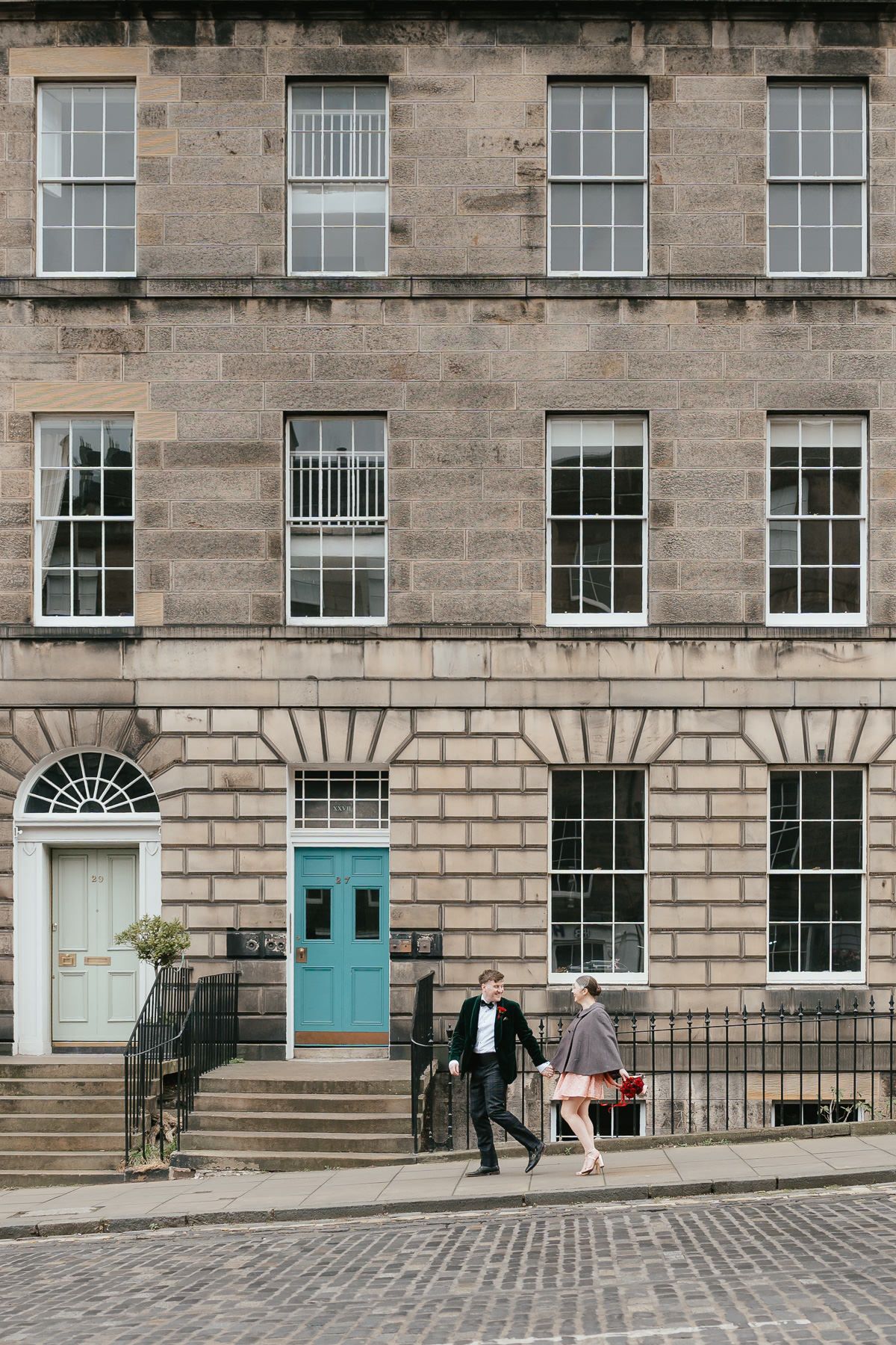 Historic Edinburgh tenement building with Georgian architecture features, stone facade, and turquoise painted doors.