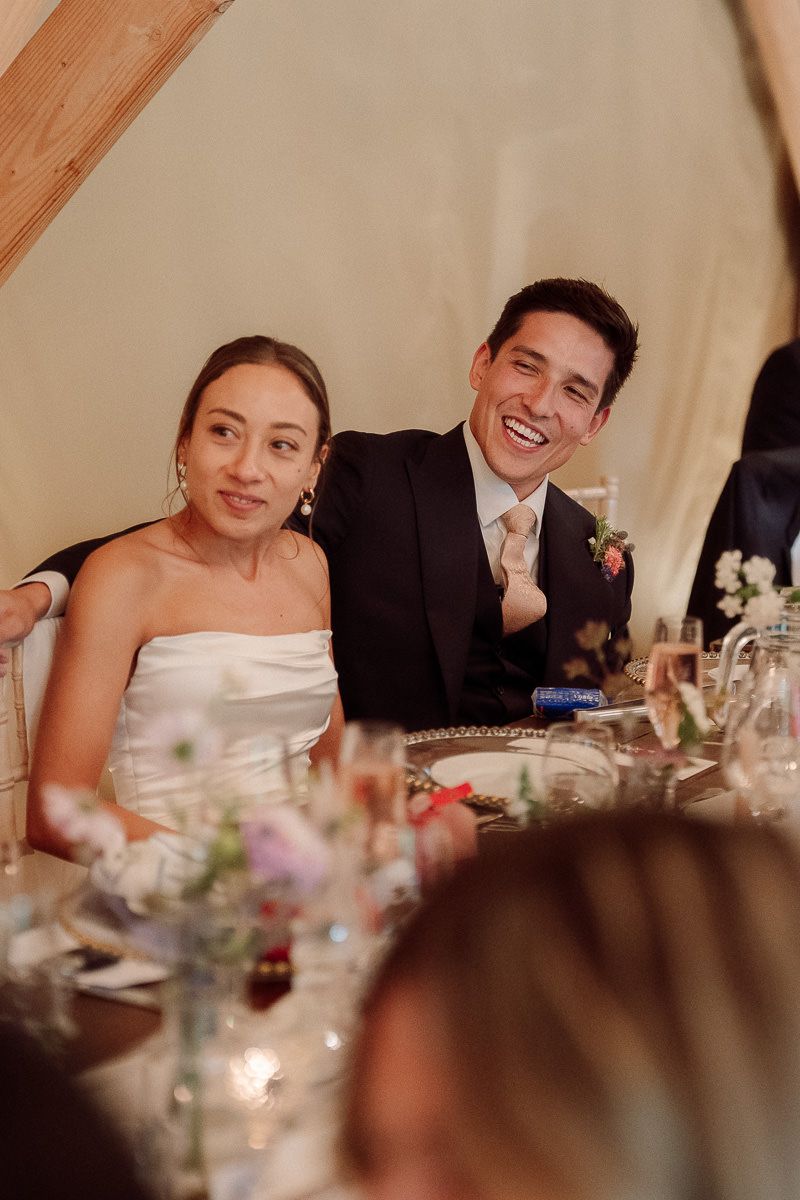 A happy couple shares an intimate moment at their wedding reception dinner table, surrounded by decorative centerpieces.