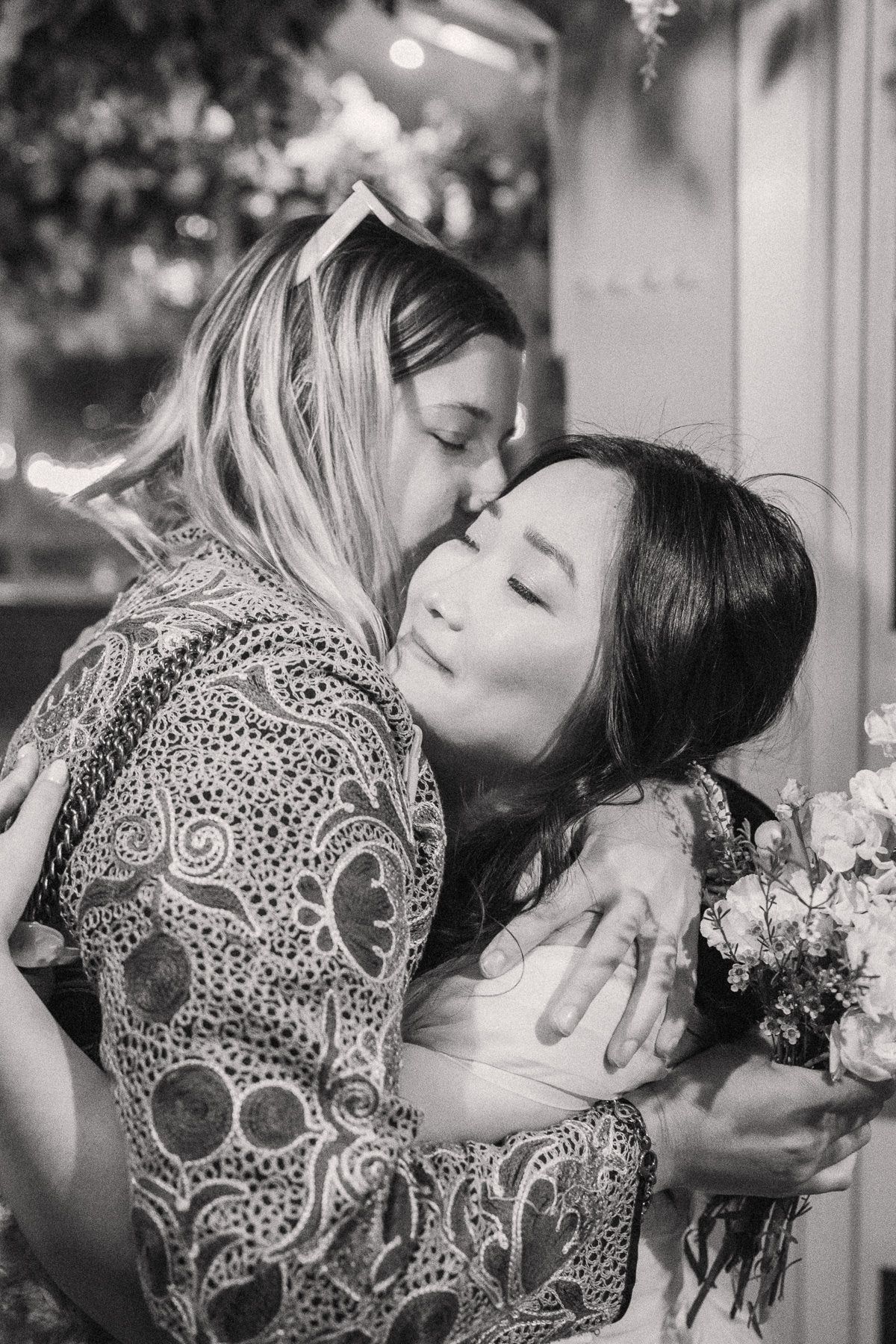 Two women embracing affectionately in a black and white photograph.