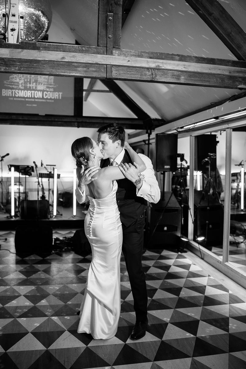 A black and white sequence of dance moves on a checkered floor shows two people performing together in an elegant space.