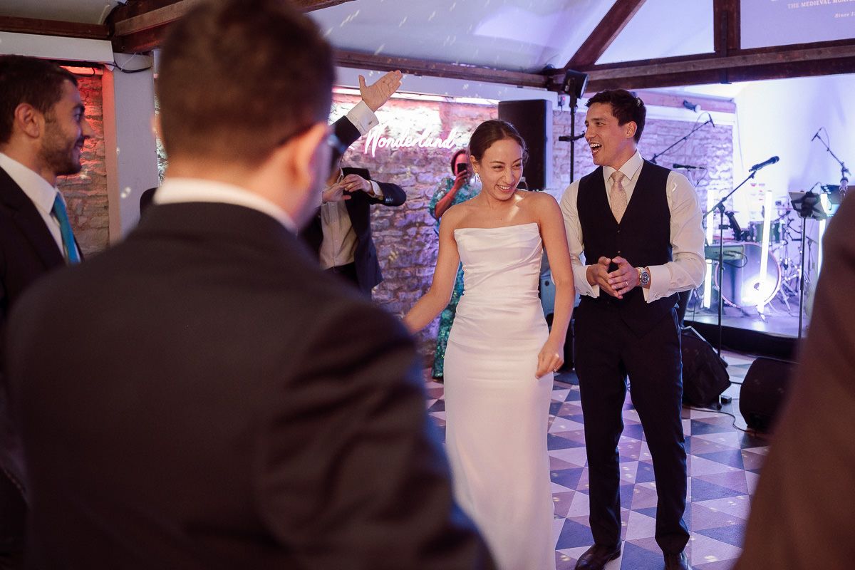 A couple celebrates at their wedding reception in a rustic venue with exposed brick walls and mood lighting.