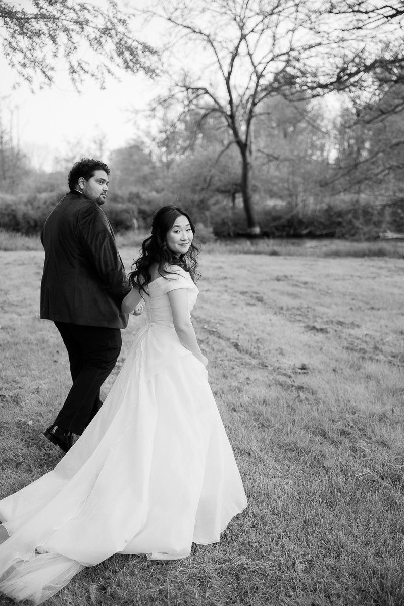 Black and white photo sequence shows a couple in wedding attire dancing playfully in a grassy field.